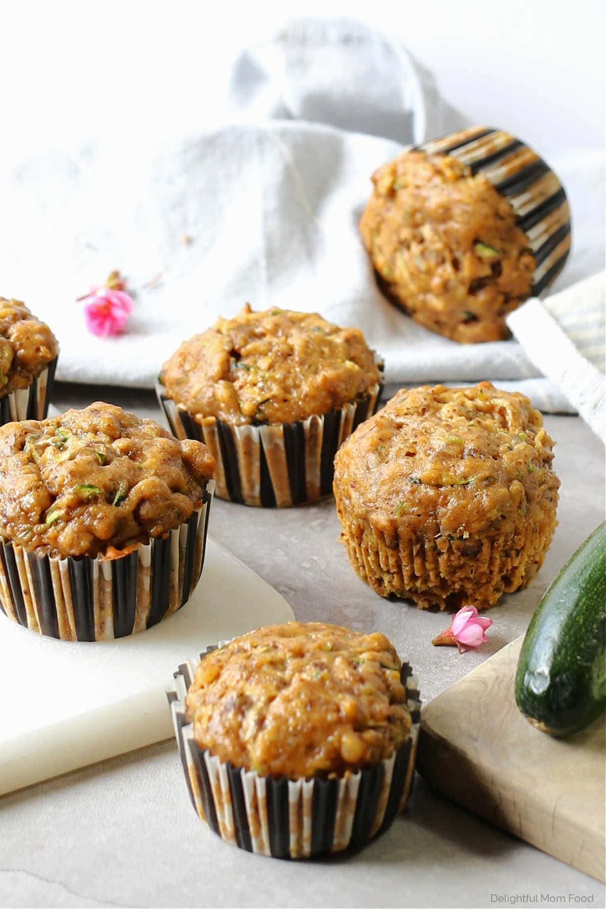gluten free zucchini pumpkin muffins surrounded by cutting boards pink flower and fresh zucchini