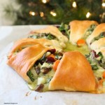 cranberry, spinach mushroom stuffed crescent roll wreath on parchment paper