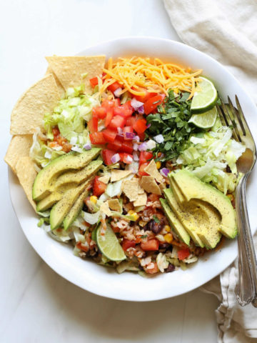 Black bean taco salad in a bowl with avocado slices and tortilla chips