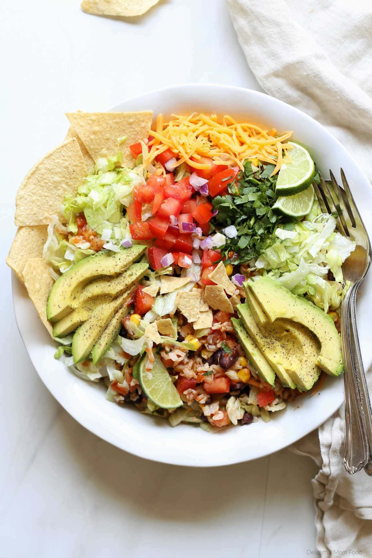 Black bean taco salad in a bowl with avocado slices and tortilla chips.
