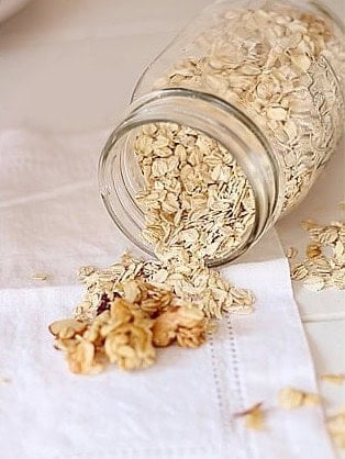 Jar of old fashioned rolled oats spilling onto a napkin for the granola base.