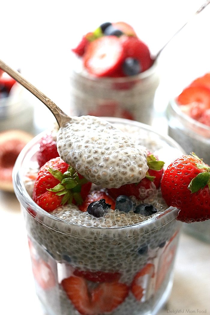 scooping pudding with chia seeds and berries out of a jar