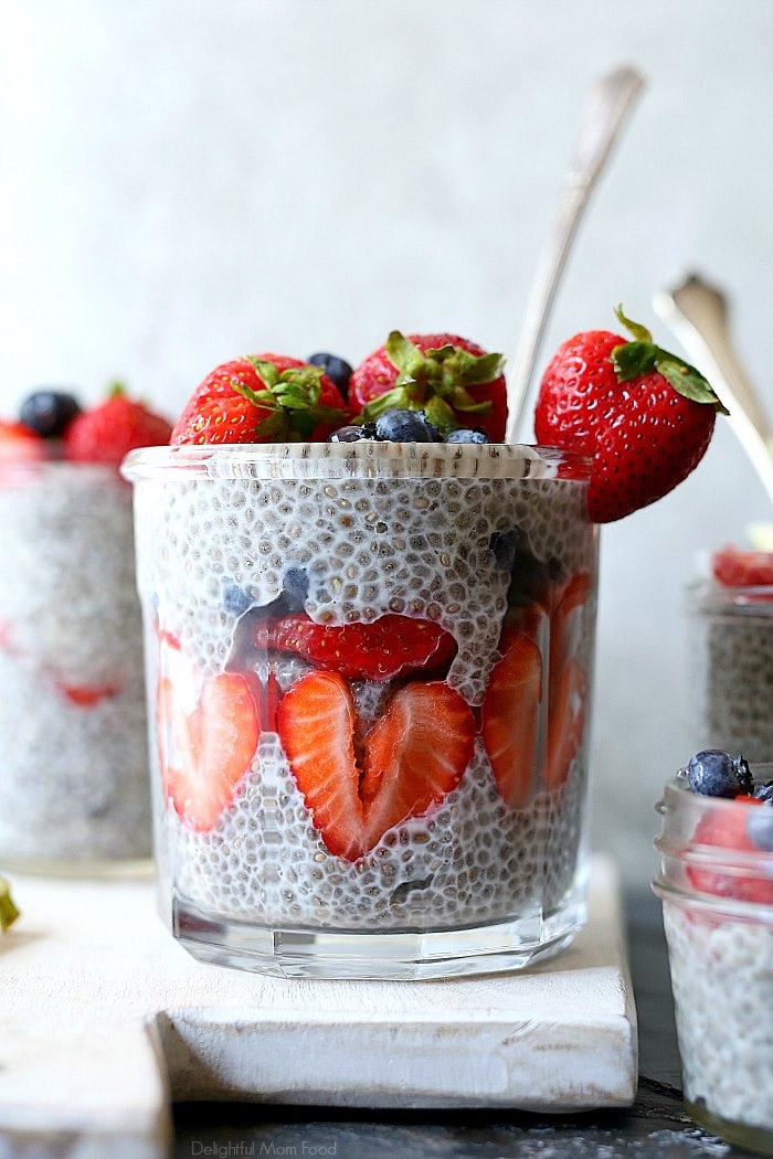 vegan chia seed pudding with fresh strawberries and blueberries in a jar with a spoon