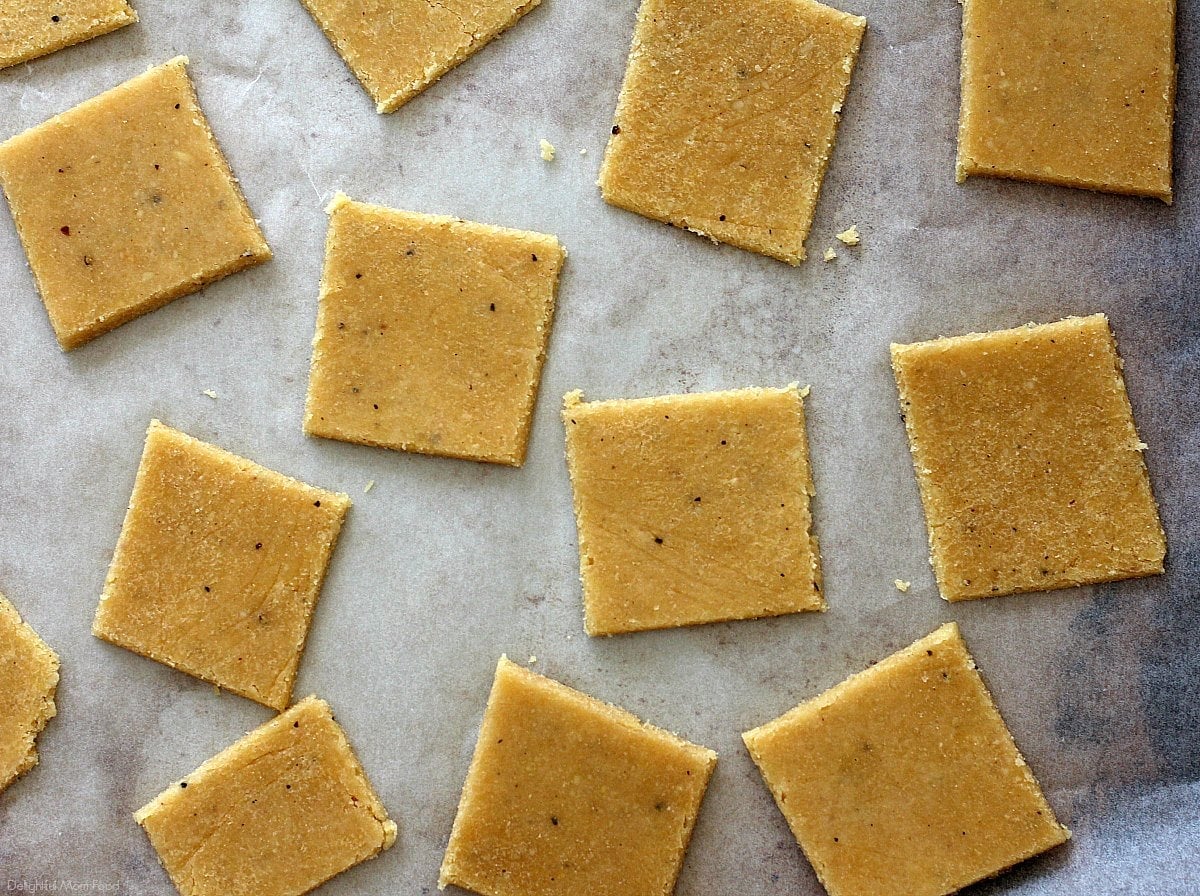 Keto cracker dough cut into squares on a baking pan.