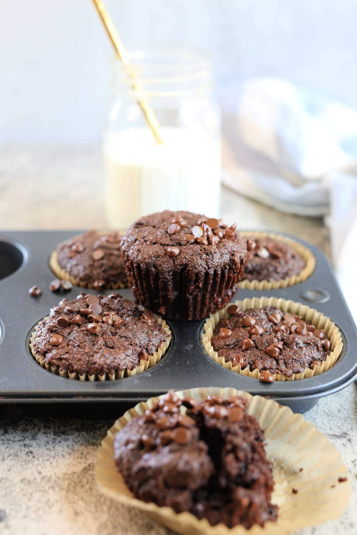 Flourless Chocolate Muffins in a muffin pan with a glass of milk in the background