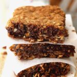 Caramel Chocolate Oat Bars stacked with wax paper between each square