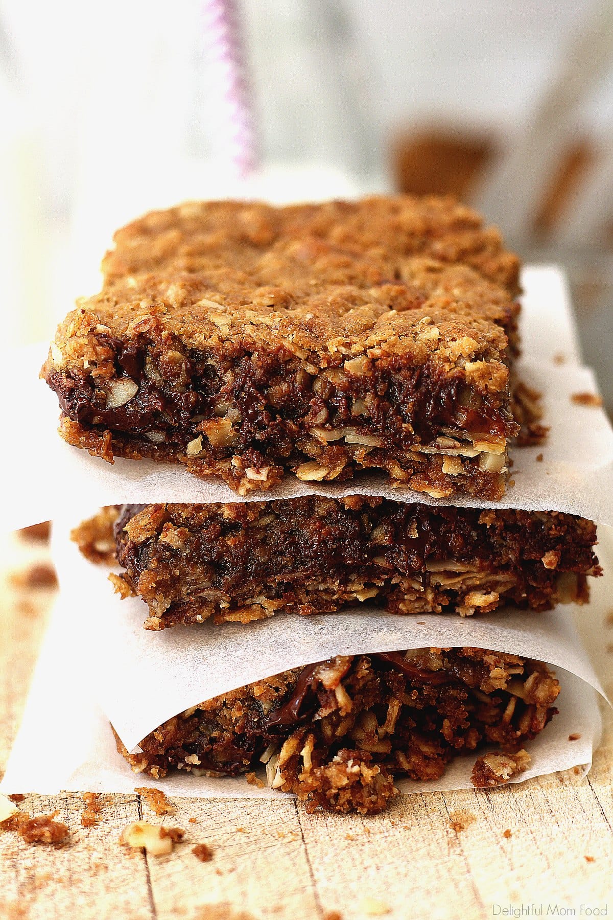 Caramel Chocolate Oat Bars stacked with wax paper between each square