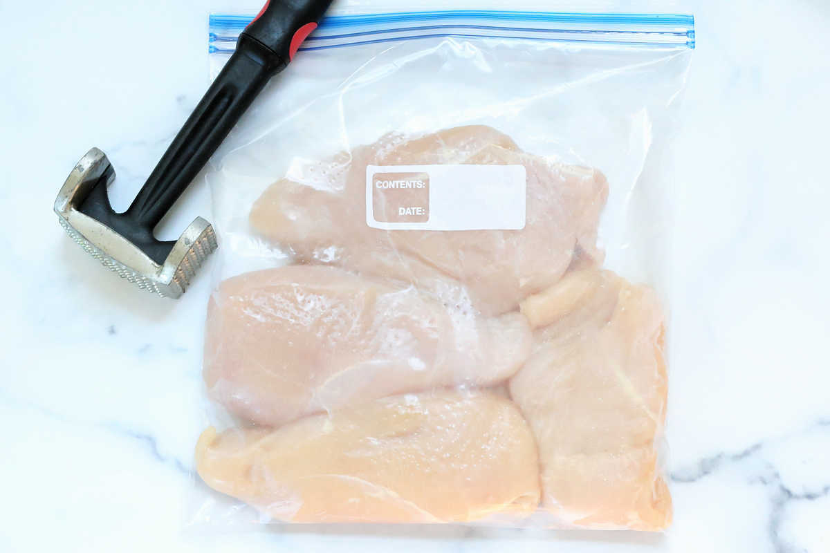 tenderizing chicken breasts in a sealed bag with a meat tenderizer