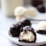 homemade chocolate covered coconut balls mound bars on a plate with a bite taken
