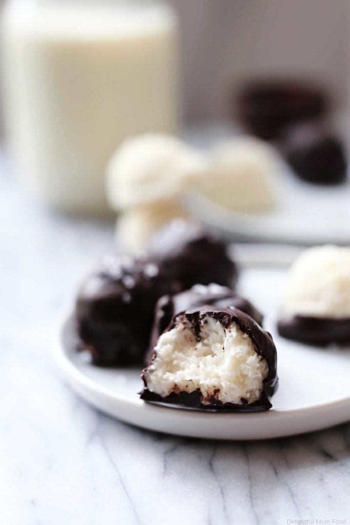 homemade chocolate covered coconut balls mound bars on a plate with a bite taken