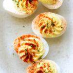 deviled eggs topped with paprika and chives