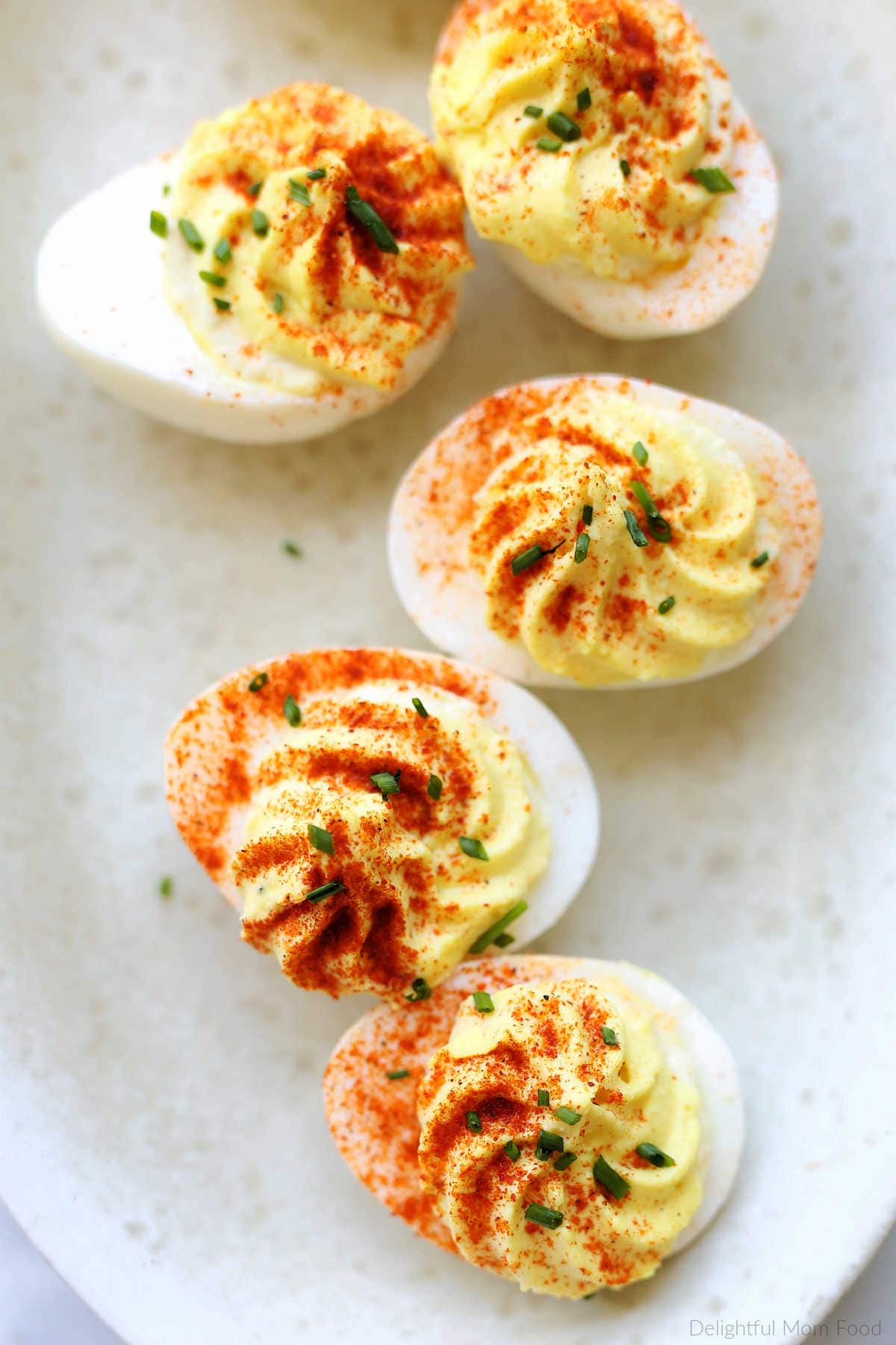 Deviled eggs topped with paprika and chives.