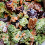 broccoli and grape salad with pecans and shredded carrots tossed in creamy dressing in a bowl