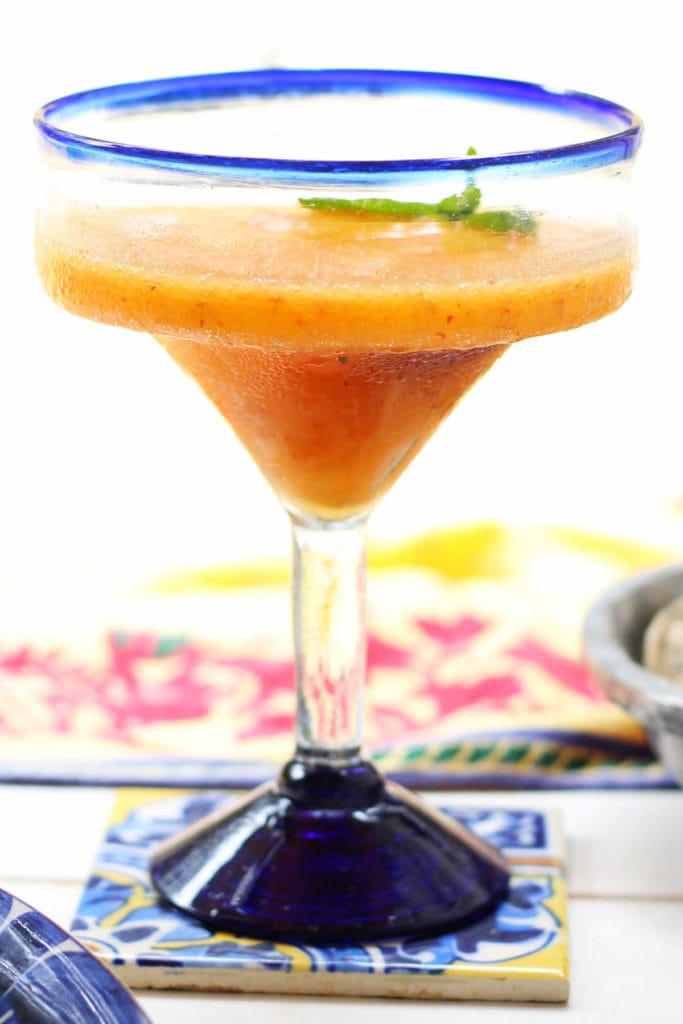 healthy frozen peach margarita recipe served in a margarita glass with a blue rim