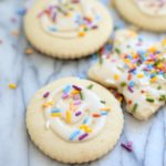 cut out gluten free sugar cookies decorated with white icing and rainbow sprinkles