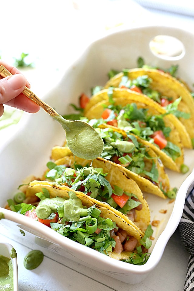 Mexican rice, beans, cheese, lettuce, cilantro and tomatoes stuffed into hard shell tacos and topped with a creamy green vegan sauce. Super easy and healthy recipe for hard shell tacos in under 30 minutes!