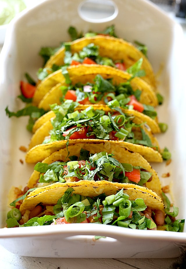 Mexican rice, beans, cheese, lettuce, cilantro and tomatoes stuffed into hard shell tacos and topped with a creamy green vegan sauce. Super easy and healthy recipe for hard shell tacos in under 30 minutes