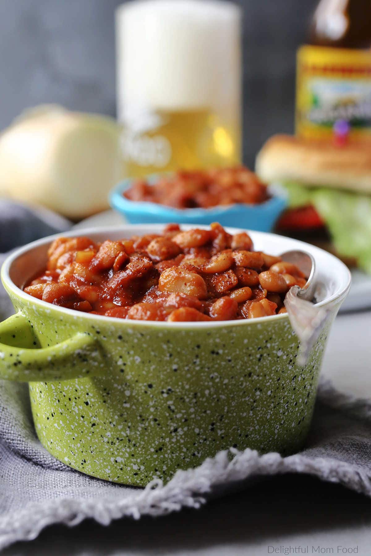 Boston style homemade gluten free baked beans in sauce in a green bowl on a towel