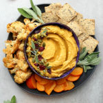 pumpkin hummus served with oil on top served with crackers and vegetables