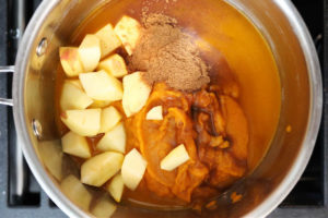 Pot on the stove with ingredients showing how to make homemade pumpkin butter.