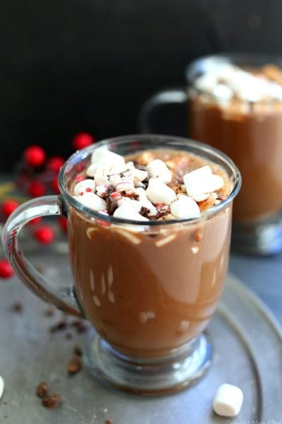 two mugs filled with the best vegan hot chocolate recipe topped with marshmallows, chocolate and peppermint bites