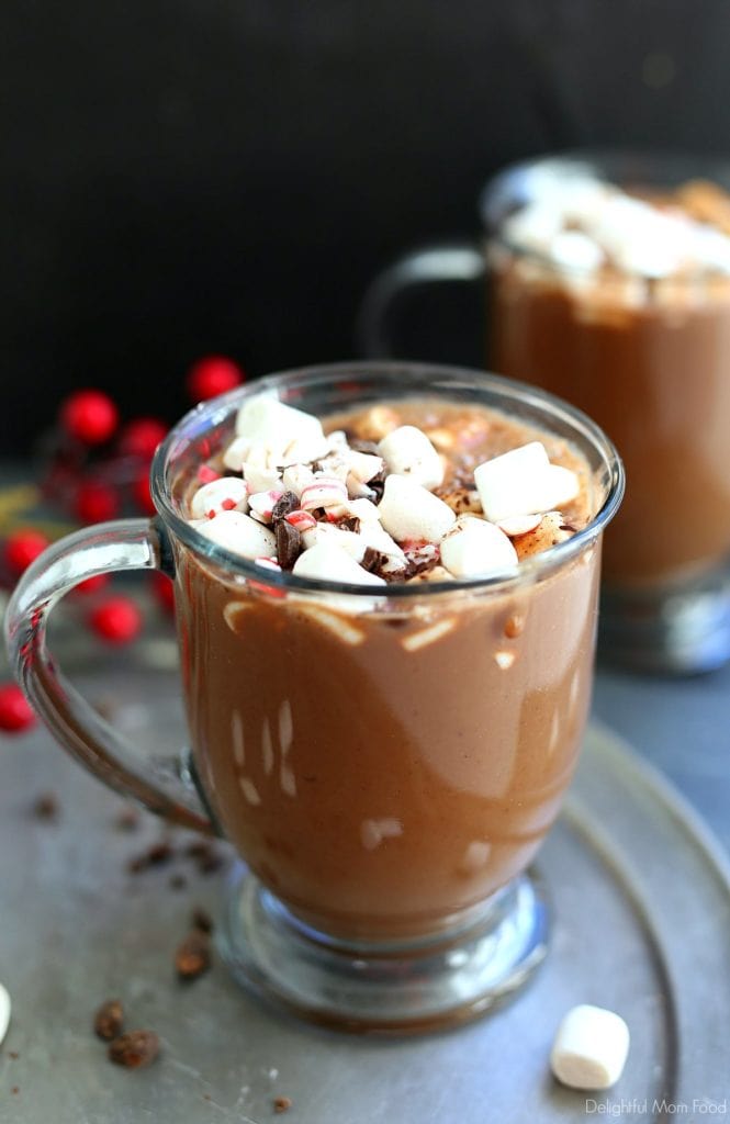 two mugs filled with the best vegan hot chocolate recipe topped with marshmallows, chocolate and peppermint bites
