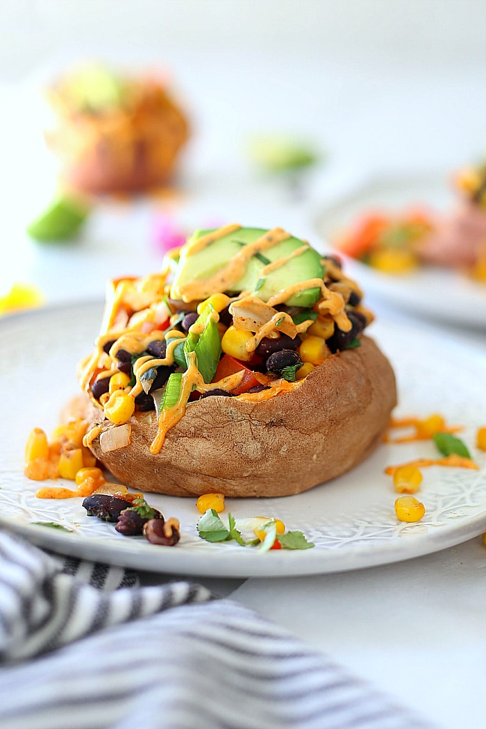 Vegan Mexican stuffed sweet potatoes with drizzled spicy southwest sauce.