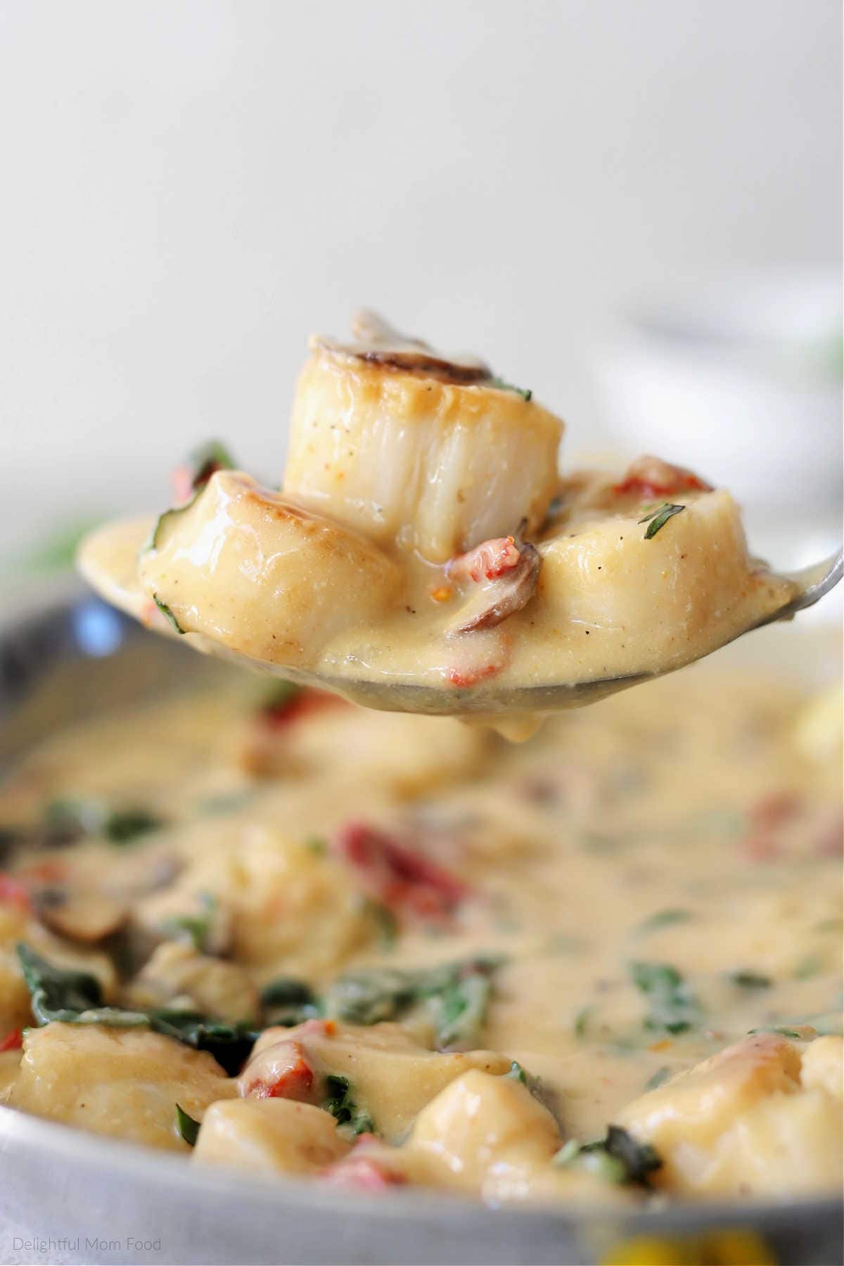 Pan seared creamy Italian flavored sea scallops on a serving spoon.