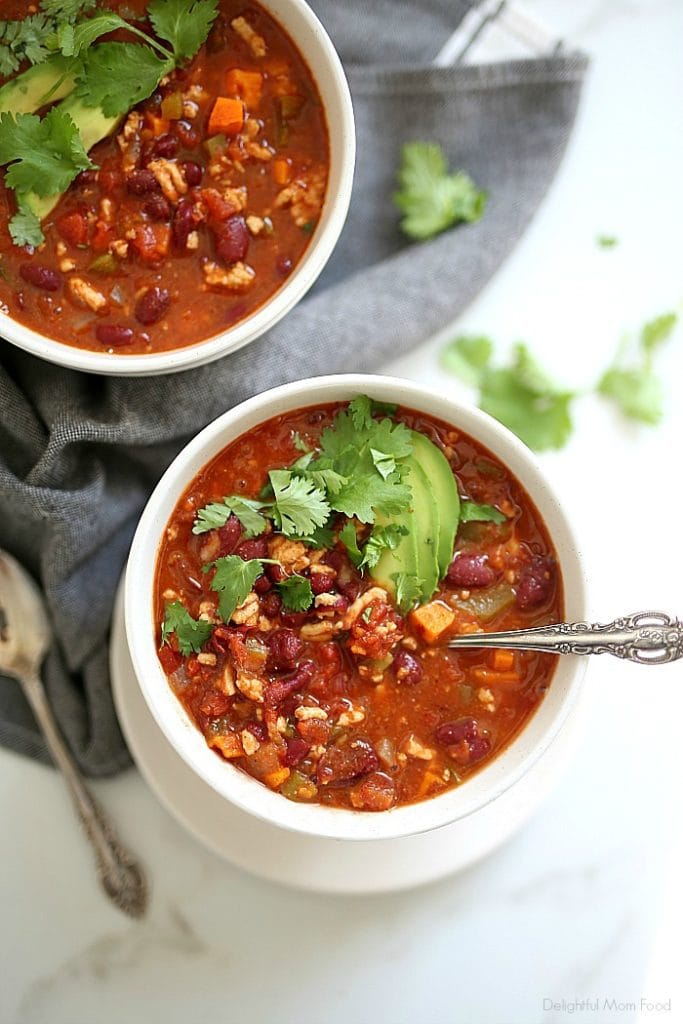 healthy turkey chili and sweet potato recipe in bowls with avocado and cilantro on top