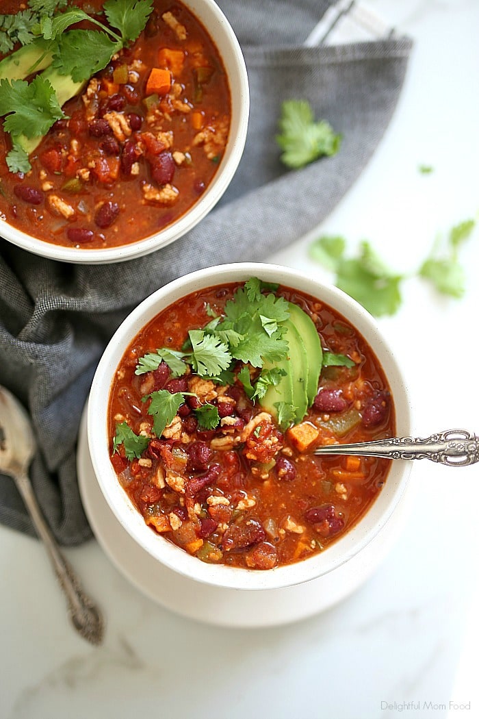 Cozy up this weekend with a comforting bowl of healthy turkey chili! This lightened up chili recipe is so easy to make and includes peppers, sweet potato, onions, tomatoes and bold seasonings that will keep you yearning for seconds! #turkeychili #healthyturkeychili #sweetpotato #groundturkey #chili #recipe #healthy #glutenfree #easy #delicious #tasty #quick | Recipe at Delightful Mom Food