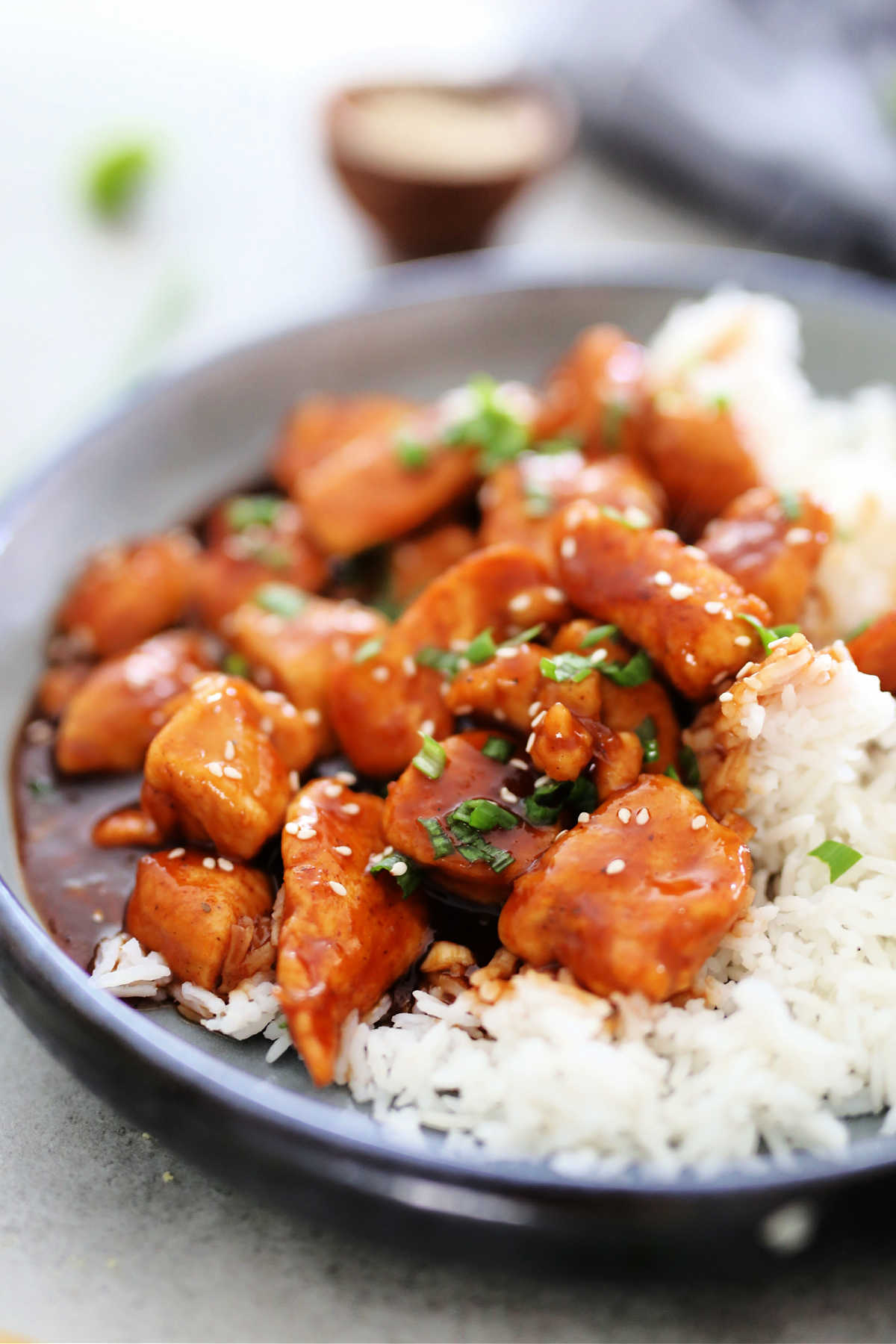 sweet and sour sauce over chicken bites topped on white rice on a plate