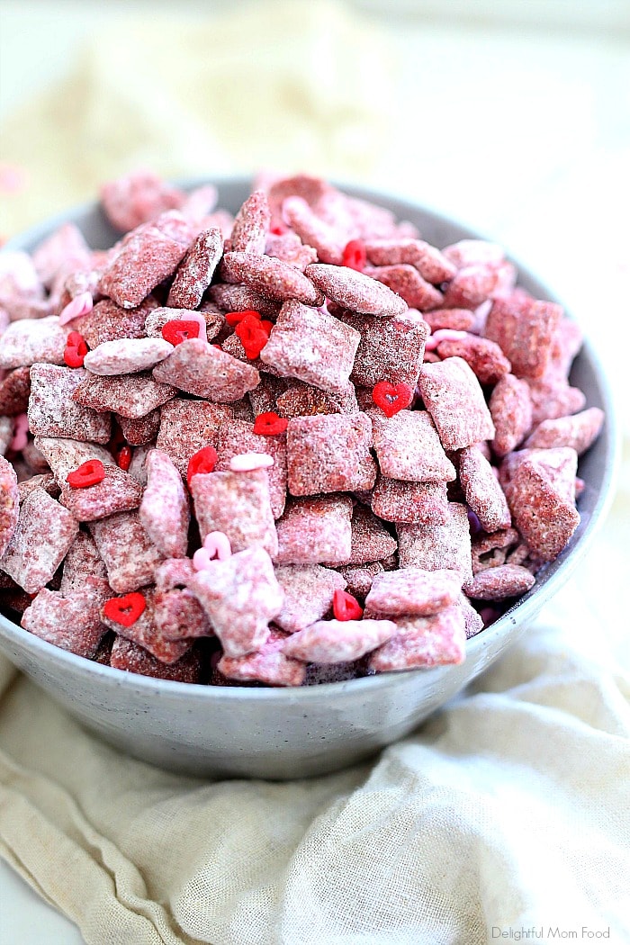 Fun and delicious pink muddy buddies (also known as puppy chow) are peanut butter, chocolate, butter, and powdered sugar coated Chex rice cereal colored with beet powder! These Valentine's muddy buddies are so simple for the kids to make and give as Valentine's Day treats to friends! #valentinesday #treats #dessert #glutenfree #quick #snack #puppychow #muddybuddies #recipe | Recipe at Delightful Mom Food