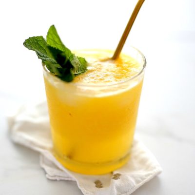 mango cocktail in a glass with mint and a straw