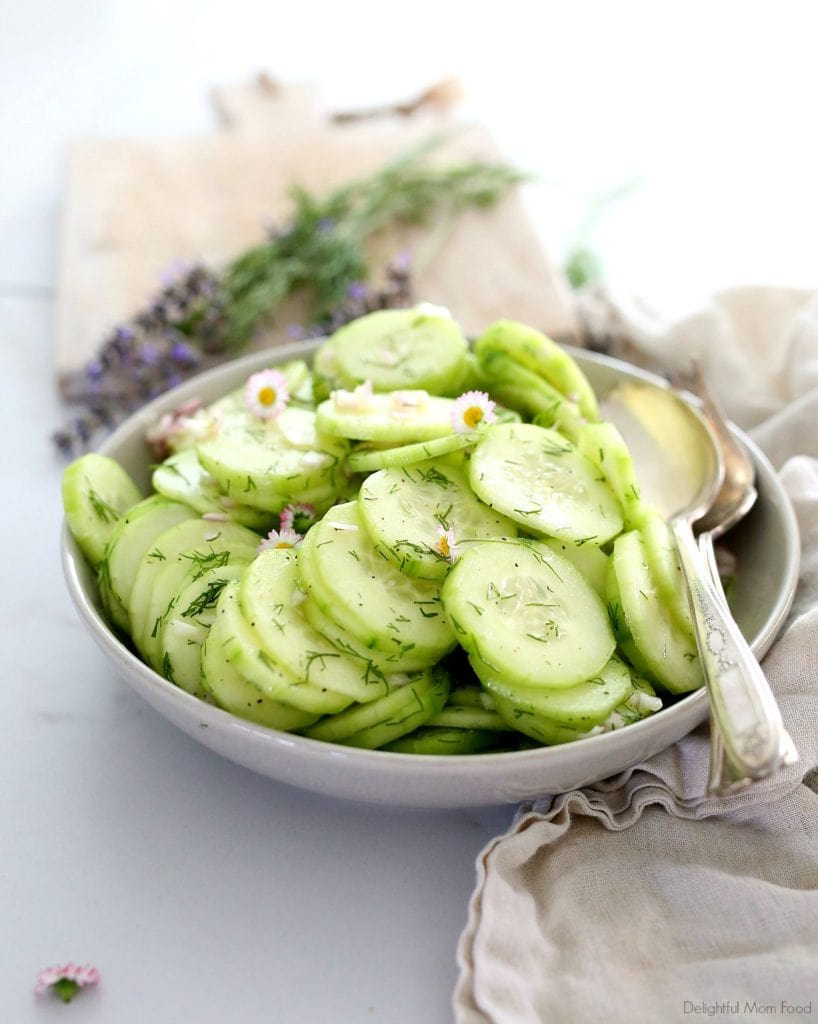 cucumber salad in a grey bowl served with serving spoons and lavender and dill in the background