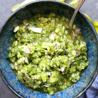 homemade tomatillo salsa in a blue bowl with a serving spoon