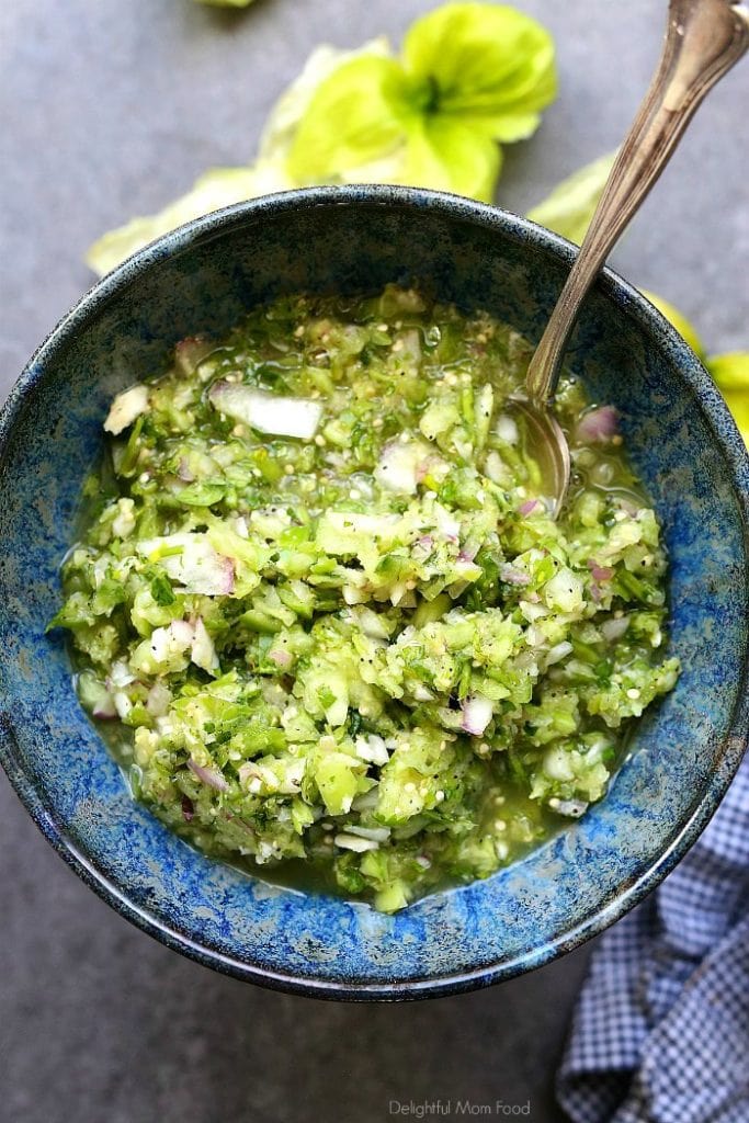 homemade tomatillo salsa in a blue bowl with a serving spoon
