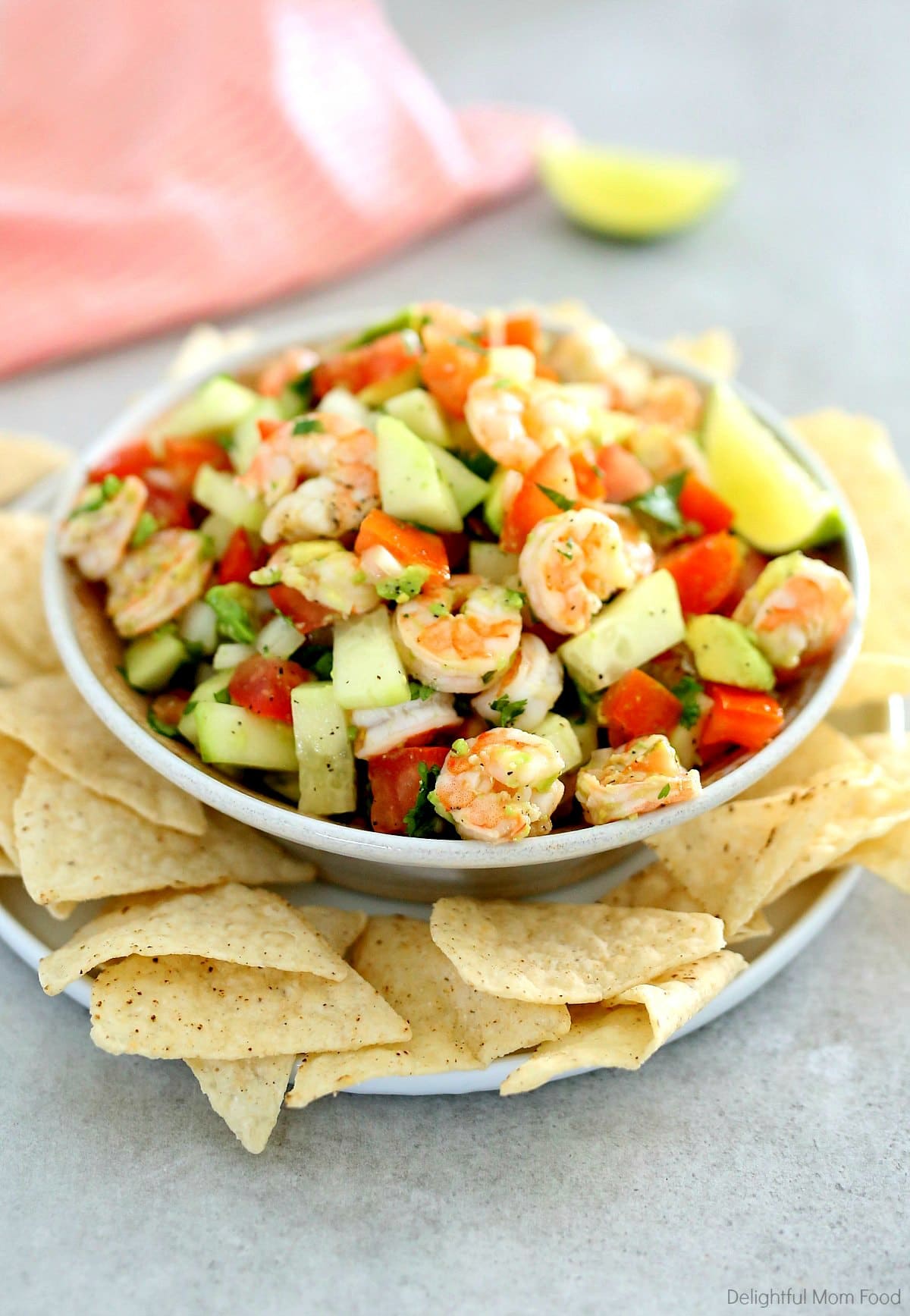 Shrimp ceviche served in a bowl with chips and a peach dish towel.