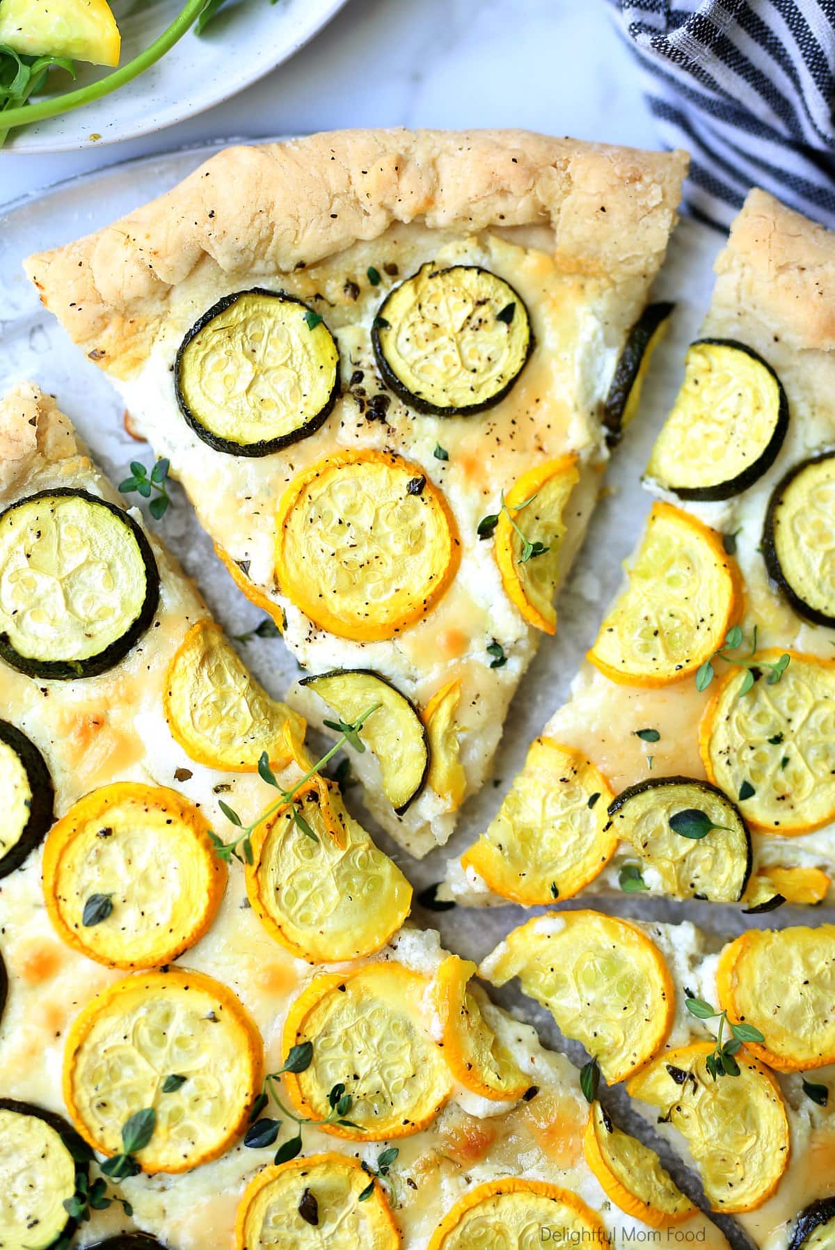 Slice of gluten-free zucchini pizza with a white cheese spread on a pizza pan