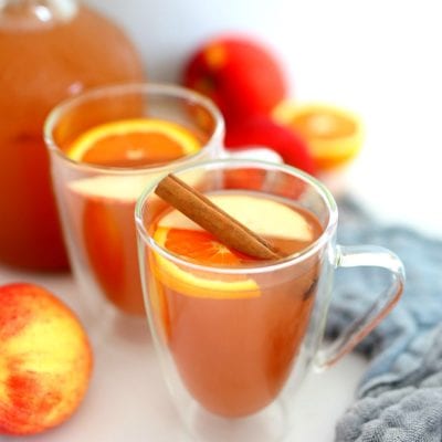 homemade apple cider in a cup with cinnamon orange and apple slices