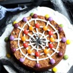 Halloween cookie cake decorated with spider web icing and candy