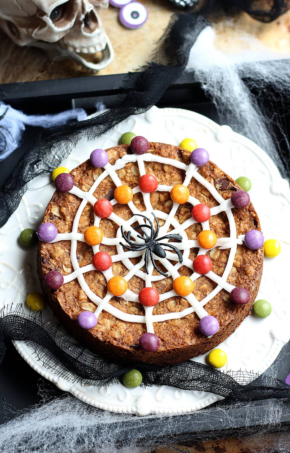 Halloween cookie cake decorated with spider web icing and candy