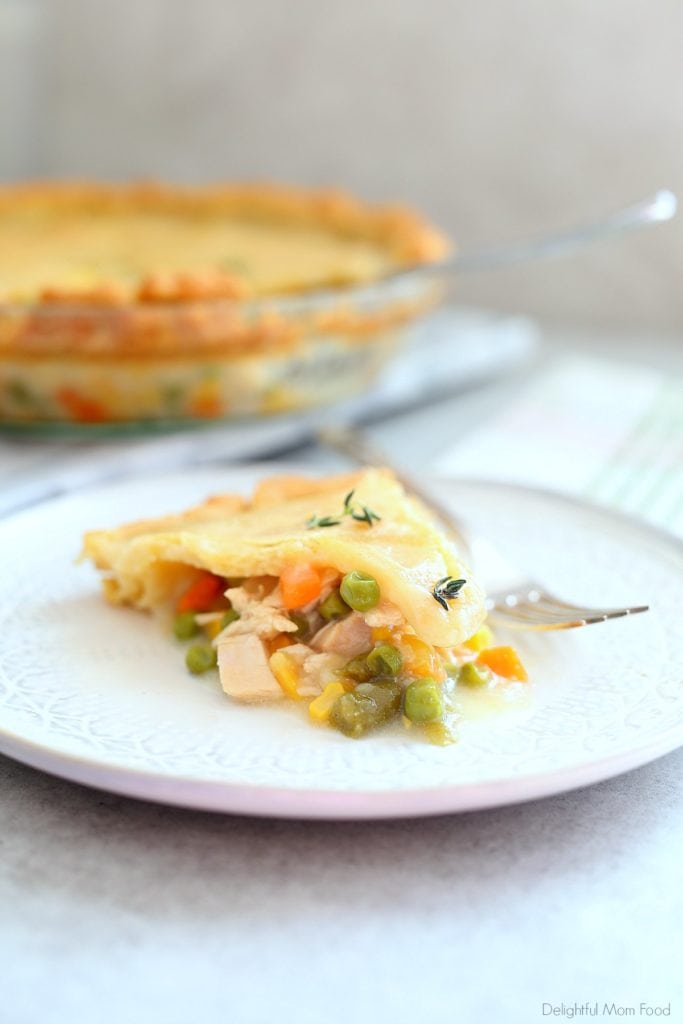 slice of gluten free chicken pot pie or turkey pot pie with fresh thyme on top and pie in the background
