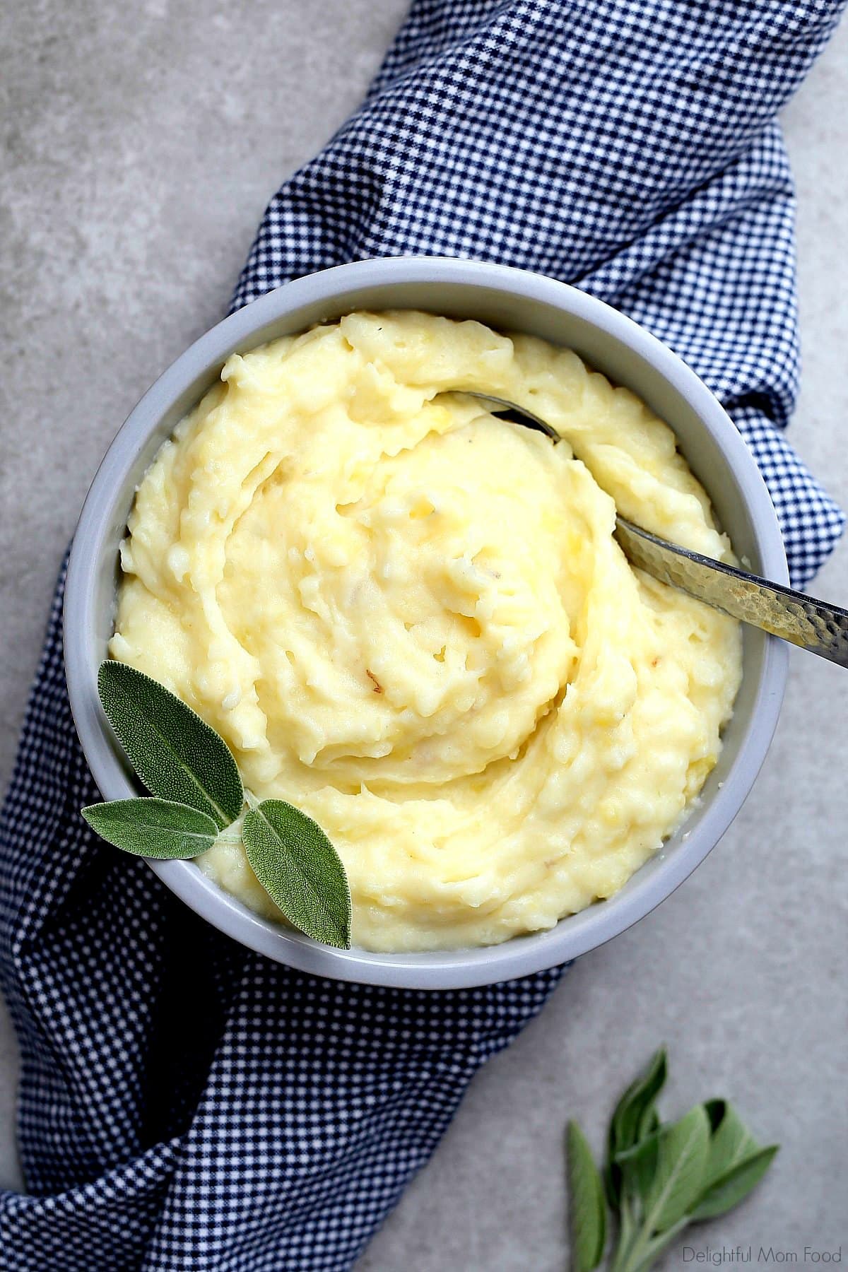sage butter infused into roasted garlic mashed potatoes mashed and mixed served in a bowl with a dish towel and fresh sage leaves