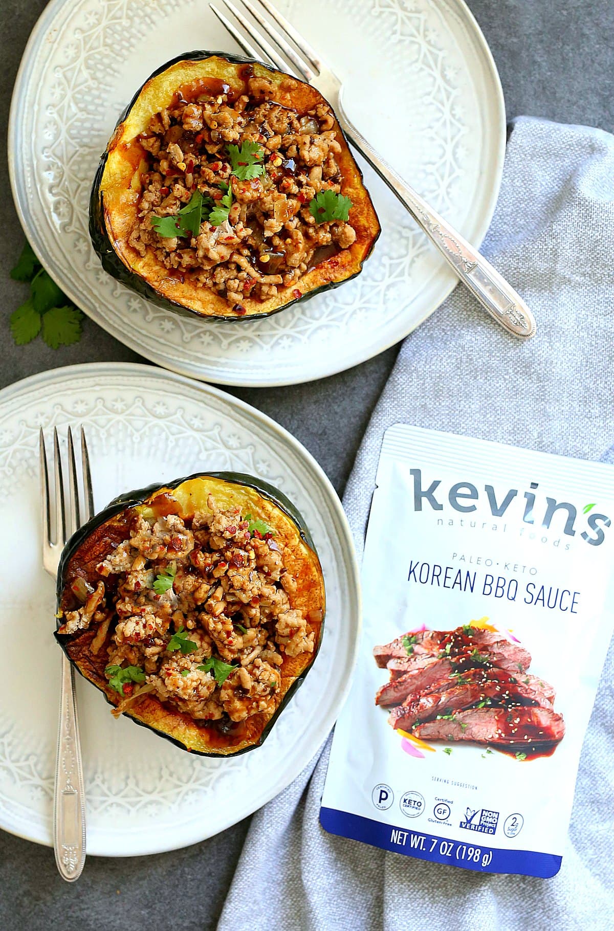stuffed acorn squash garnished with cilantro on two plates with forks