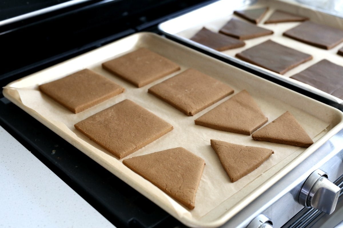 Baked gluten-free gingerbread house pieces on a parchment lined baking sheet.