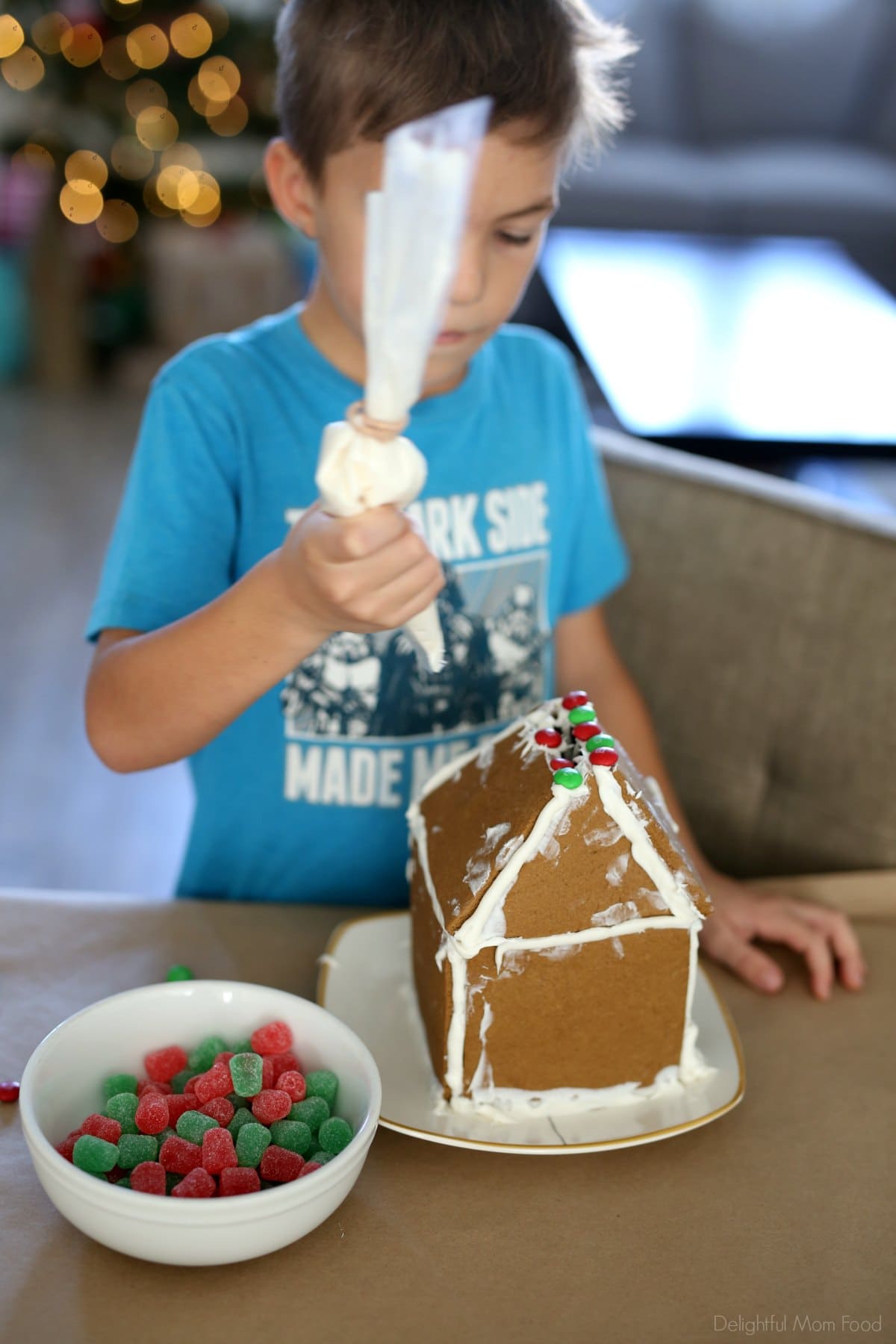 decorating a homemade gingerbread house with icing