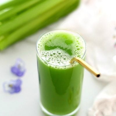 celery juice in a glass with a straw