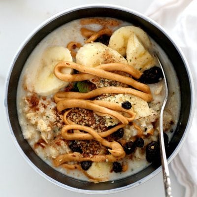 peanut butter drizzled on gluten-free oatmeal with banana slices, raisins and cinnamon