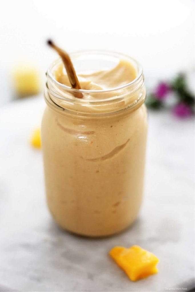 mango and jackfruit smoothie recipe that looks like a milkshake in a mason jar with gold straw