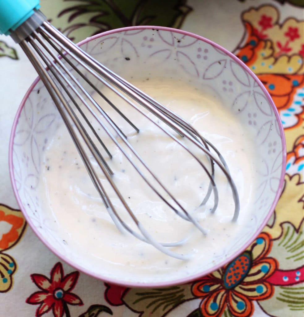 homemade creamy coleslaw dressing mixed with a whisk